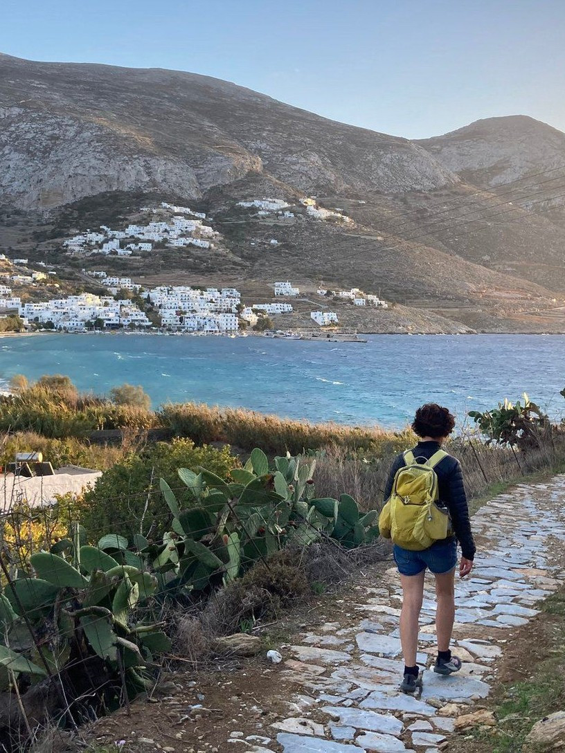 © Wilfrid Valette Escursionista su un sentiero lastricato sopra la baia di Amorgos, nelle Cicladi